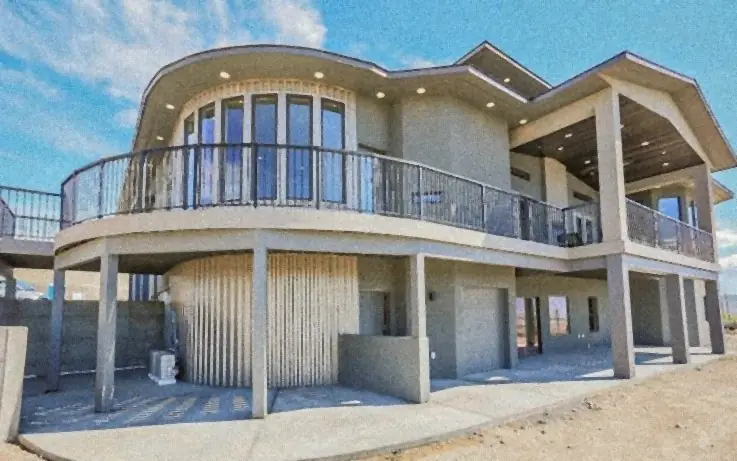 A modern home with a curved front wrapped in grey metal siding and a balcony