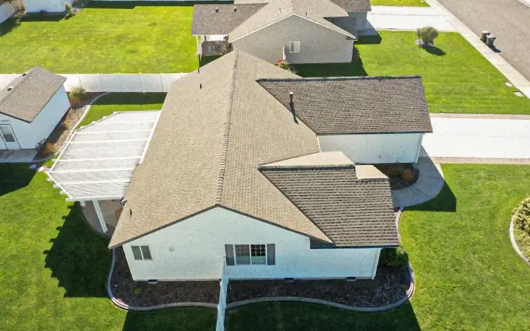 Drone view of a finished shingle roof on a single-storey home with green lawns